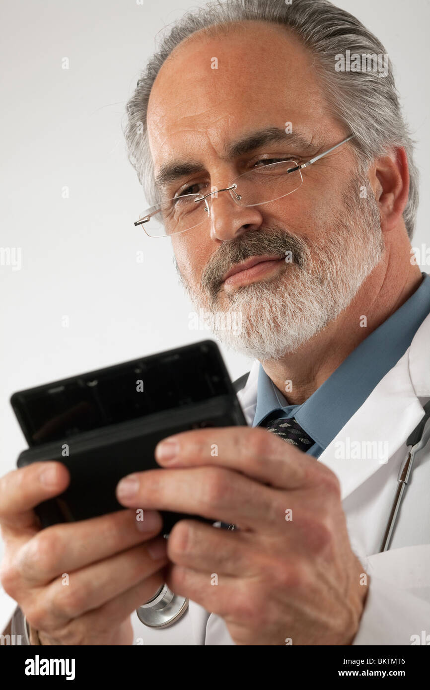 Close-up of a doctor wearing glasses and a lab coat and texting on a cell phone. Vertical shot. Stock Photo