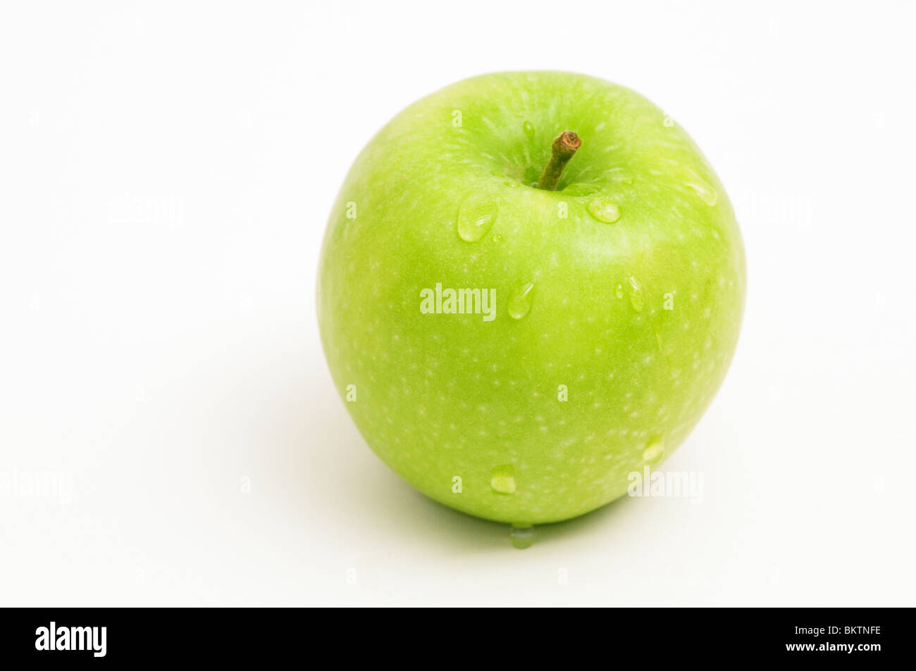 SINGLE GRANNY SMITH APPLE MALUS DOMESTICA ON WHITE BACKGROUND WITH WATER DROPLETS Stock Photo