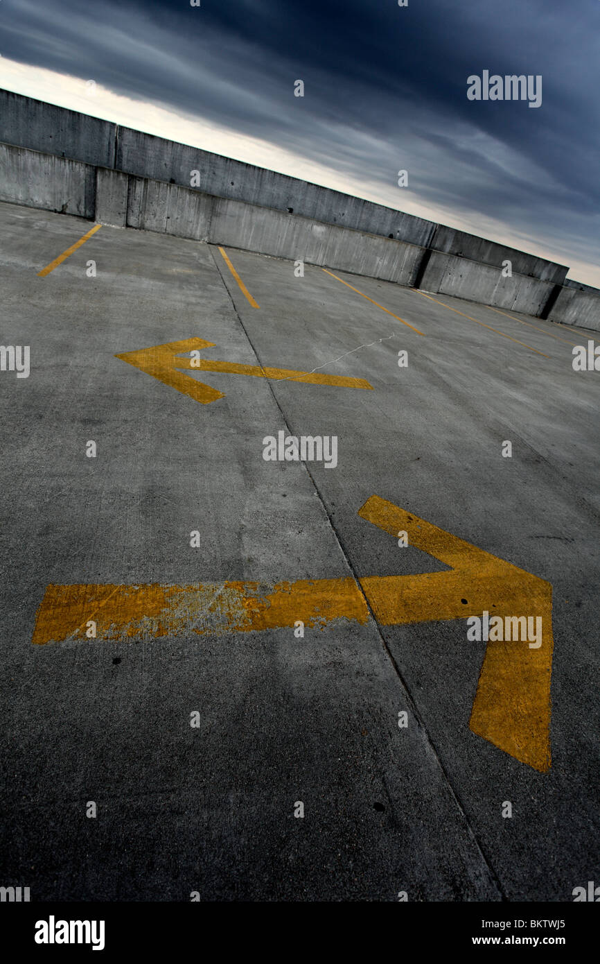 Two yellow directional arrows in parking lot. Stock Photo