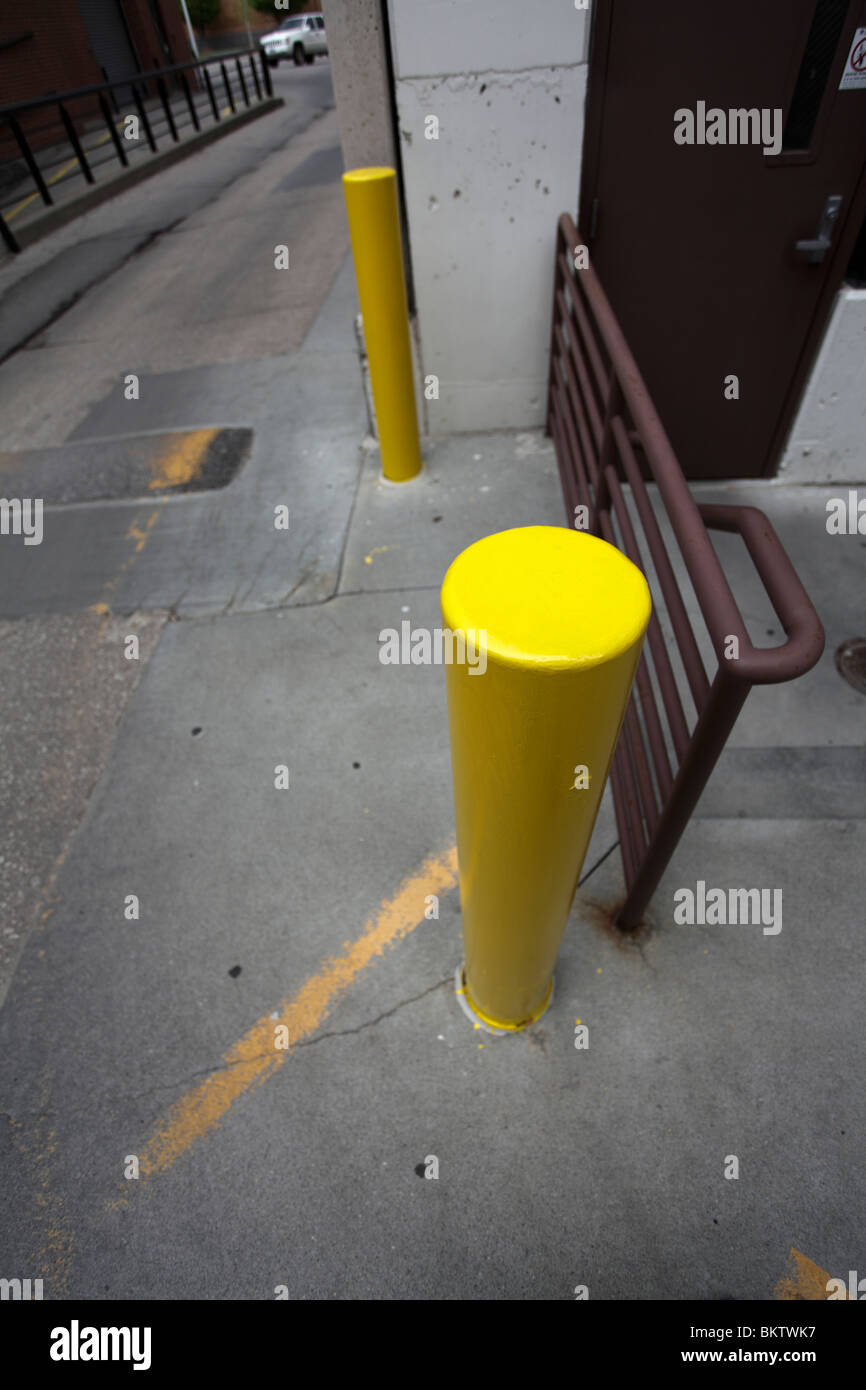 Yellow parking bollard and metal hand rail. Stock Photo