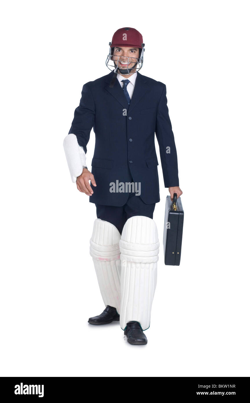 Businessman wearing sports helmet and cricket pad, smiling, portrait Stock Photo