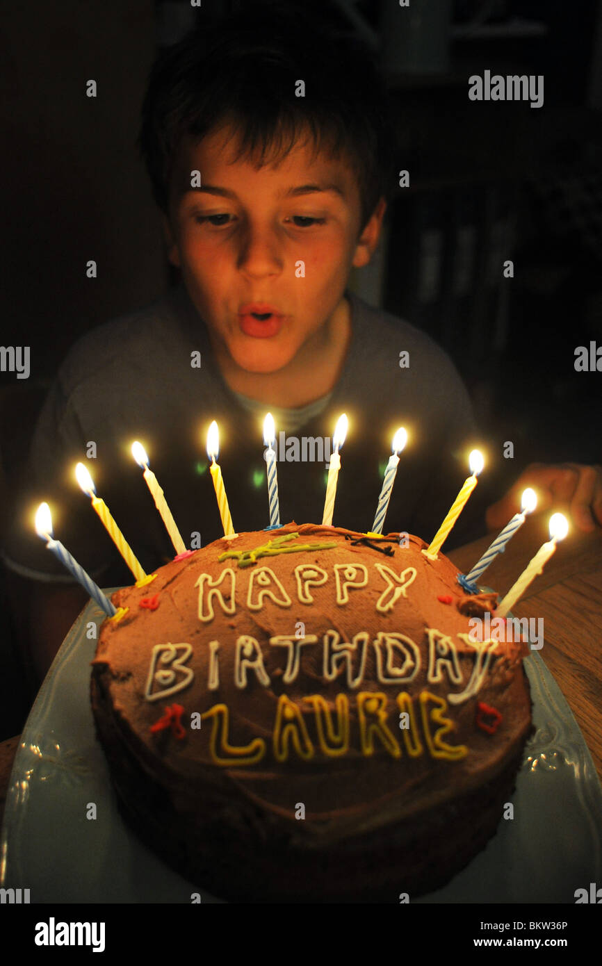A Ten year old boy blows out the candles on his birthday cake Stock