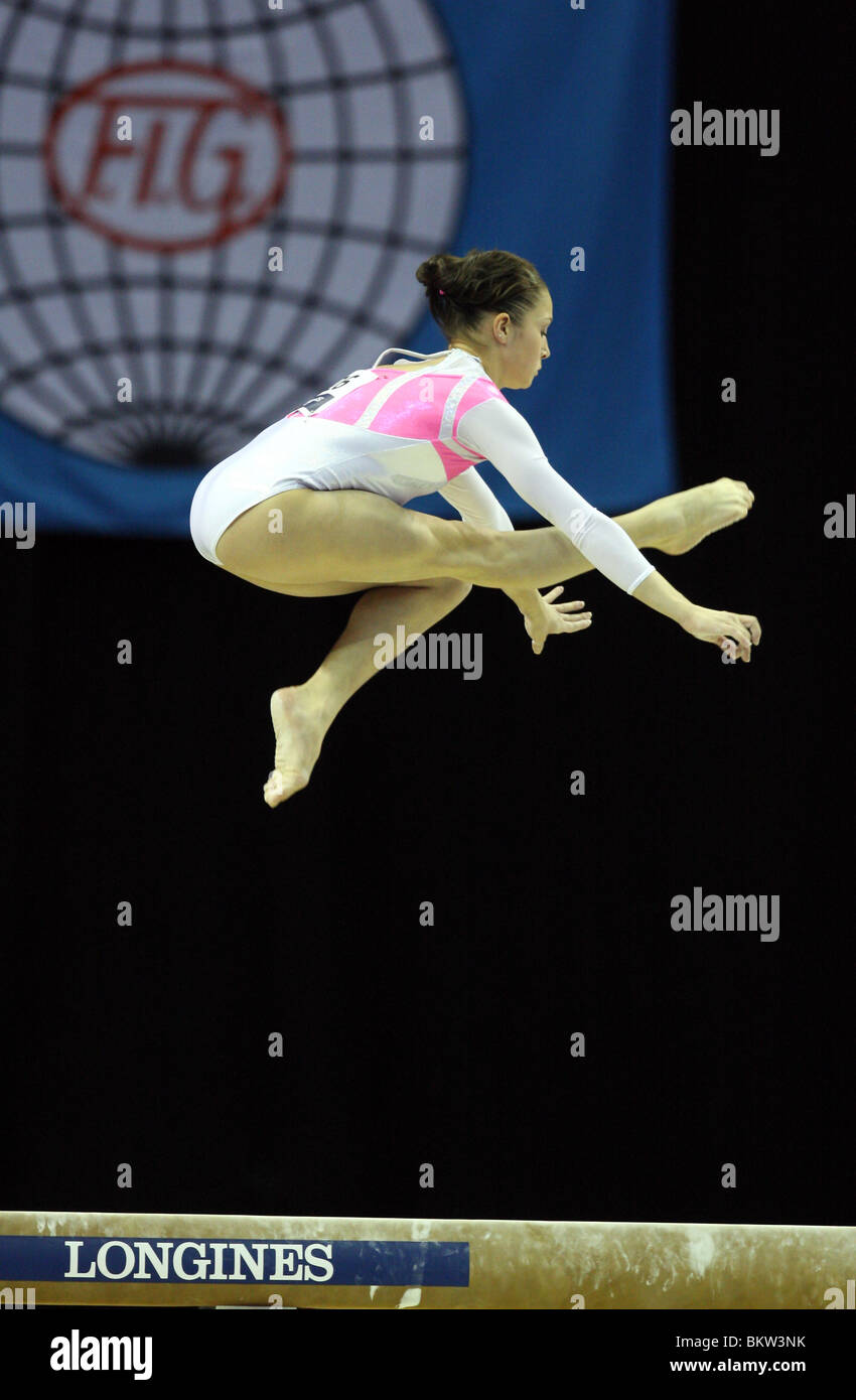 female gymnast leaps in the air while performing on the beam in a gymnastics competition Stock Photo