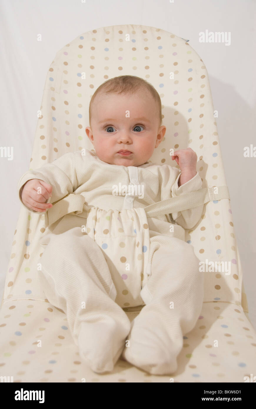 Portrait of Baby Girl Sitting in Spotted in Bouncer Chair Stock Photo