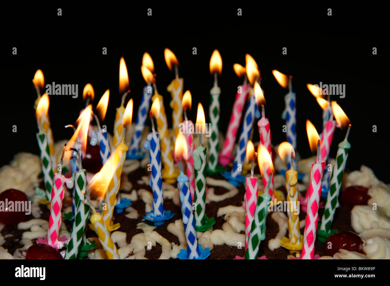 Candles on a birthday cake with a black background Stock Photo - Alamy