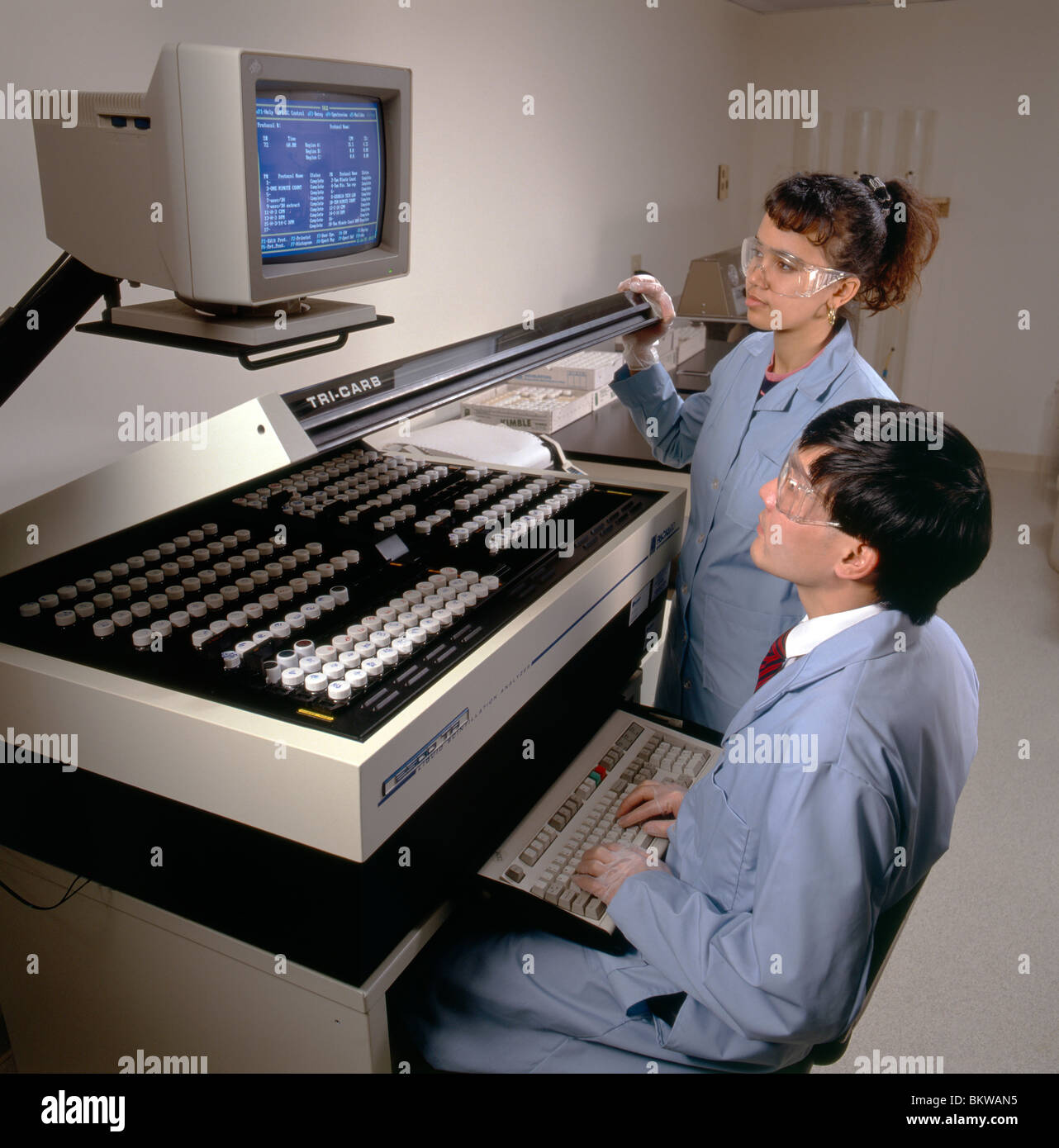 Male & female technicians using a liquid scintillation analyzer in the