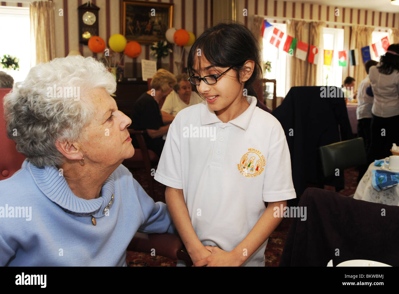 Primary School children meet elderly people at their residential home as part of a 'meet the neighbor' inter generational scheme Stock Photo