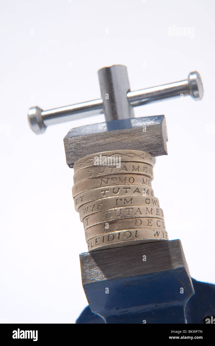 Pound under pressure, pound coins held in the grip of a vice. Stock Photo