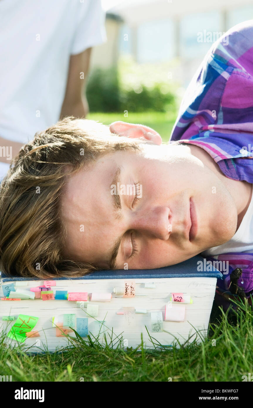 Guy lying outside resting on textbook Stock Photo