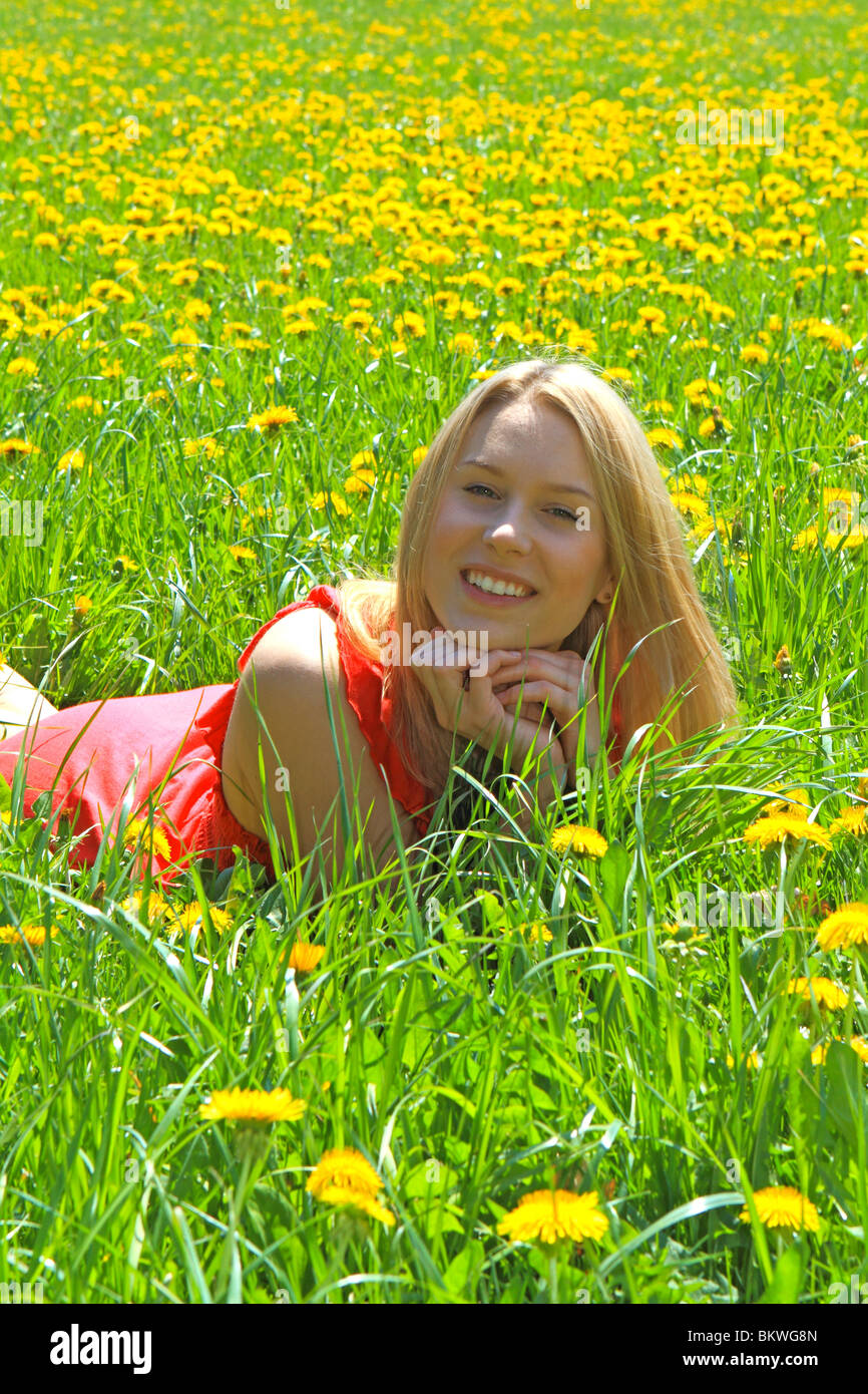 Happy young woman in spring, lying in blooming meadow Stock Photo