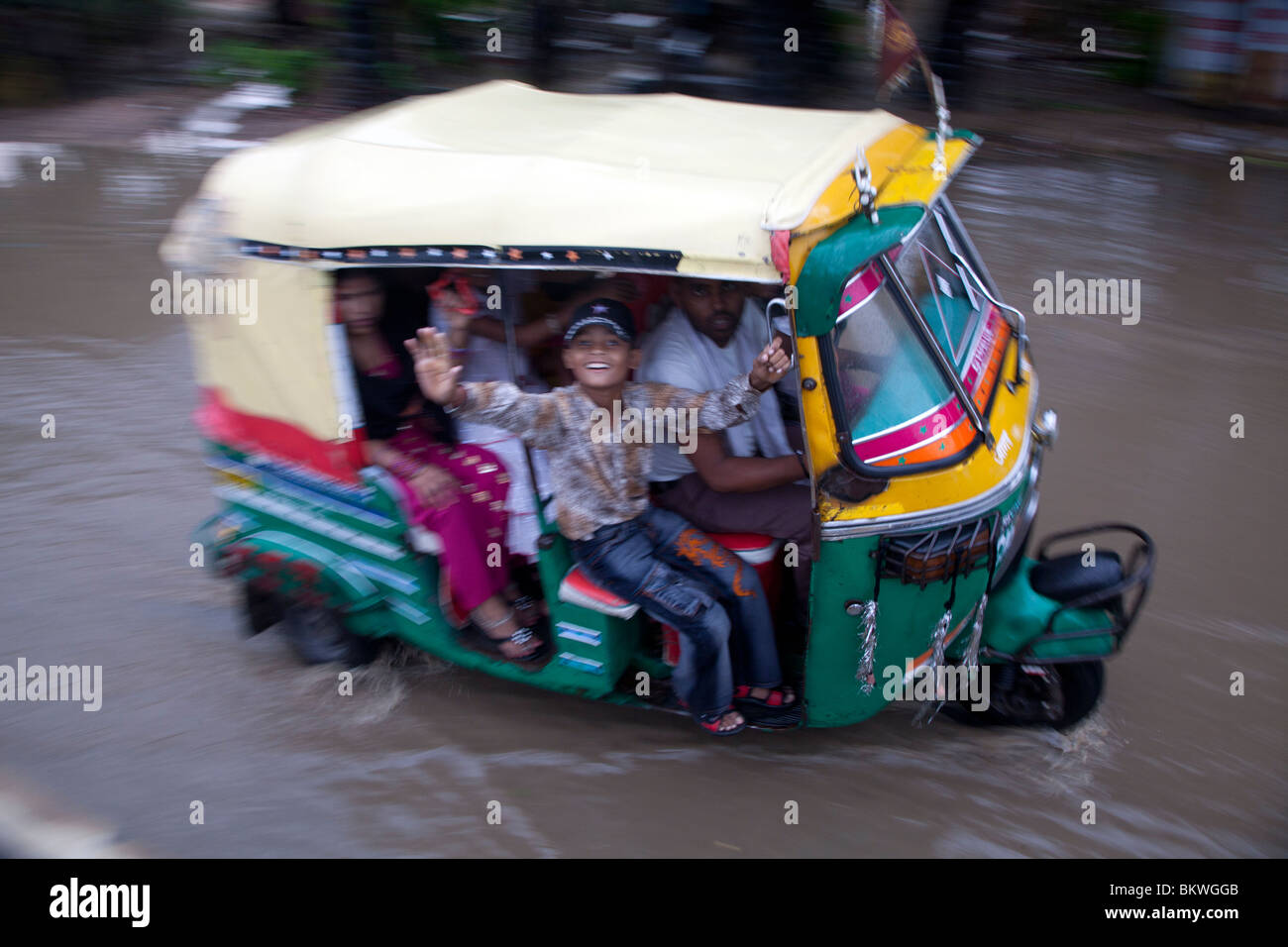 India, Uttar Pradesh, Agra, Rickshaw and passengers in heavy monsoon rain driving through flood Stock Photo