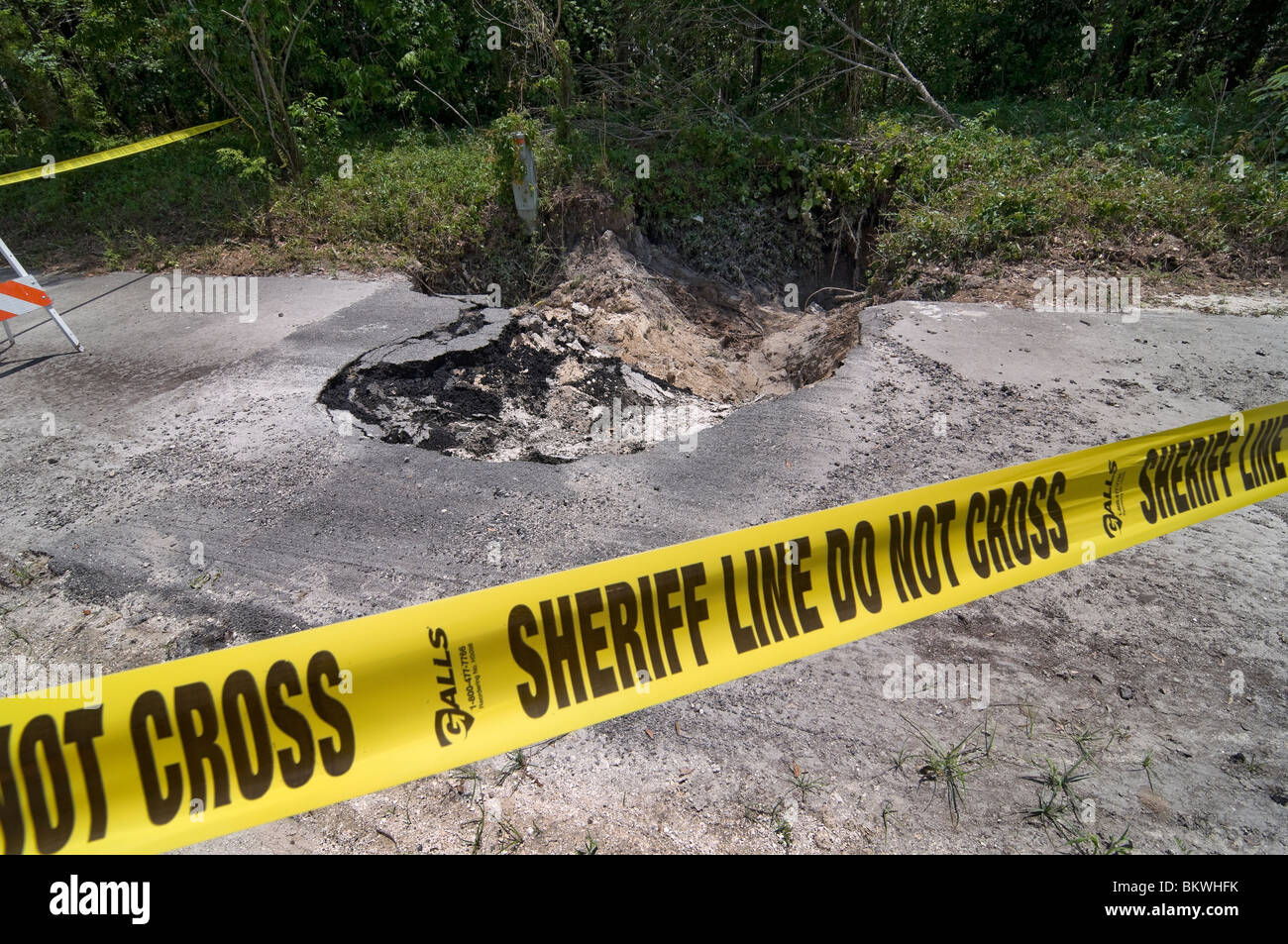 sheriff's yellow warning tape around sinkhole formed in footpath after heavy rainfall and stormy weather Branford Florida Stock Photo