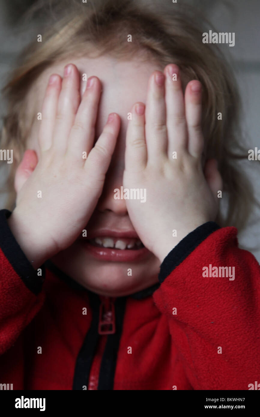 TWO YEAR OLD PEEK-A-BOO GAME: Two year old child baby girl play playing hide and seek game MODEL RELEASED Stock Photo