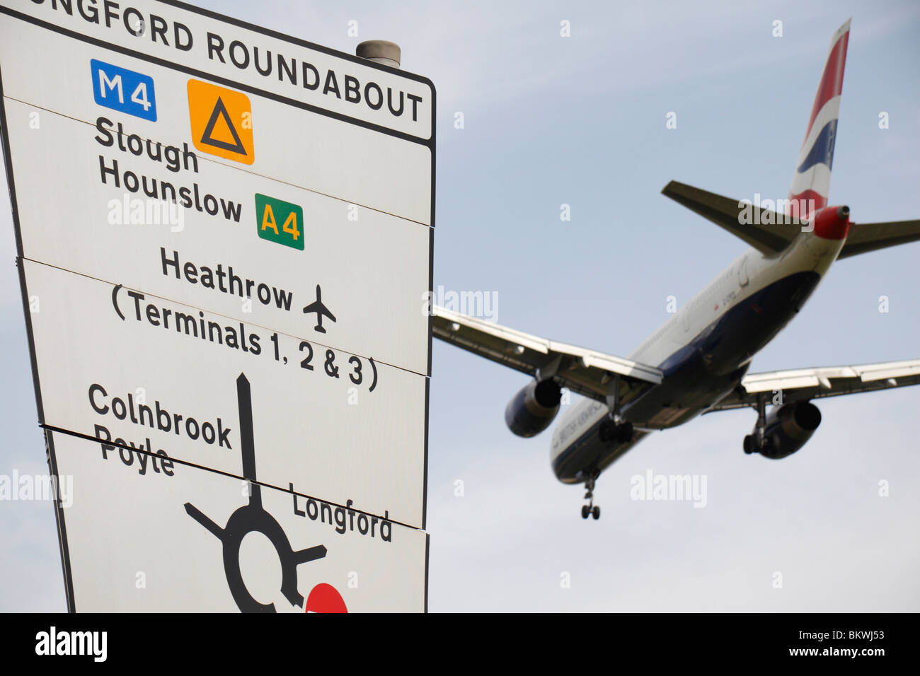A British Airways plane passing a road sign while landing at Heathrow Airport, London, UK. Stock Photo