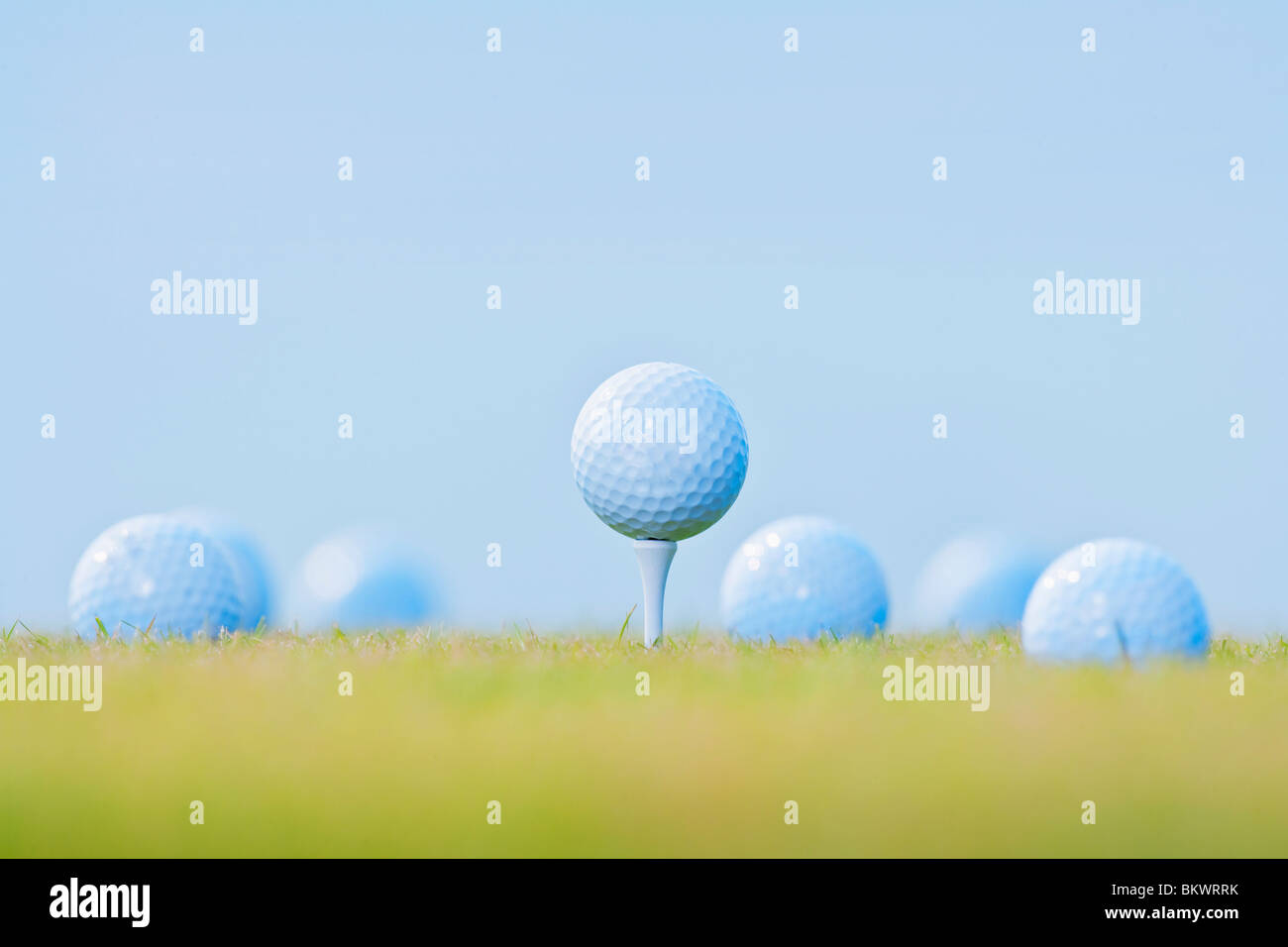 golf ball on tee surrounded by other golf balls out of focus Stock Photo