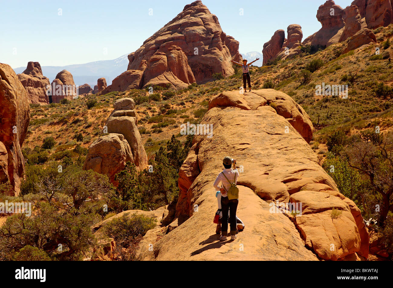 Stock photograph of Japanese tourists posing for pictures in Devils Garden, Arches National Park,  Utah, USA. - Stock Image