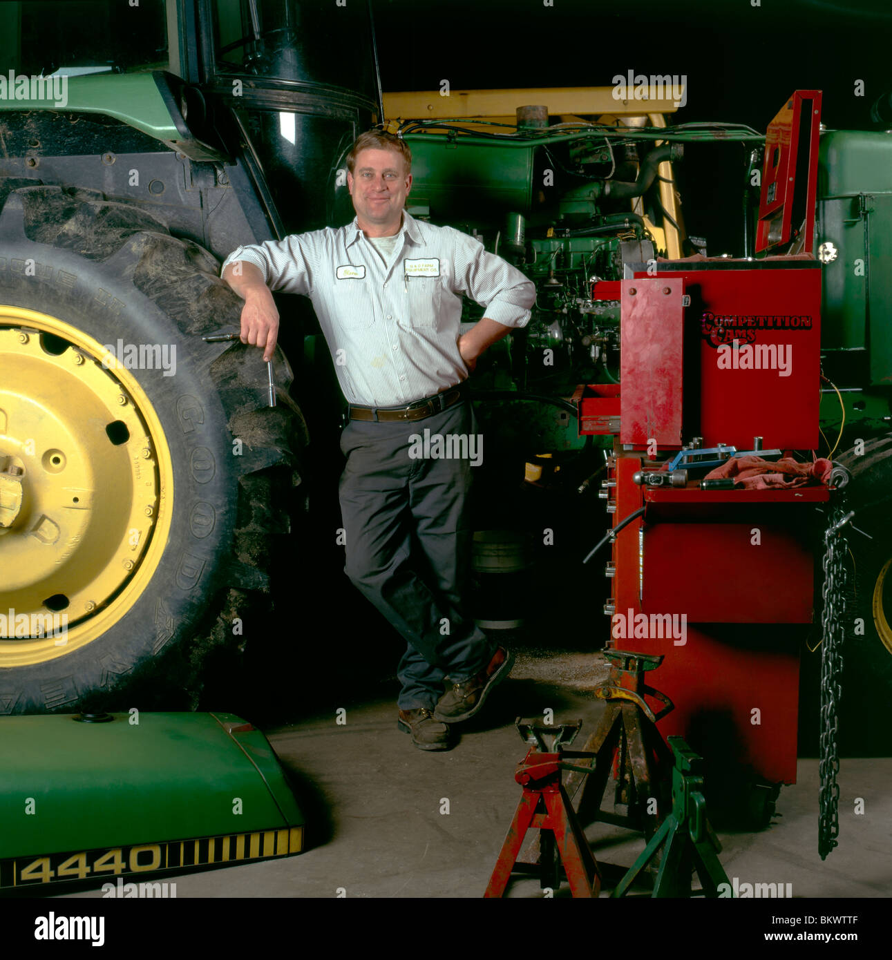 Portrait of farm equipment mechanic in his shop surrounded by tractors
