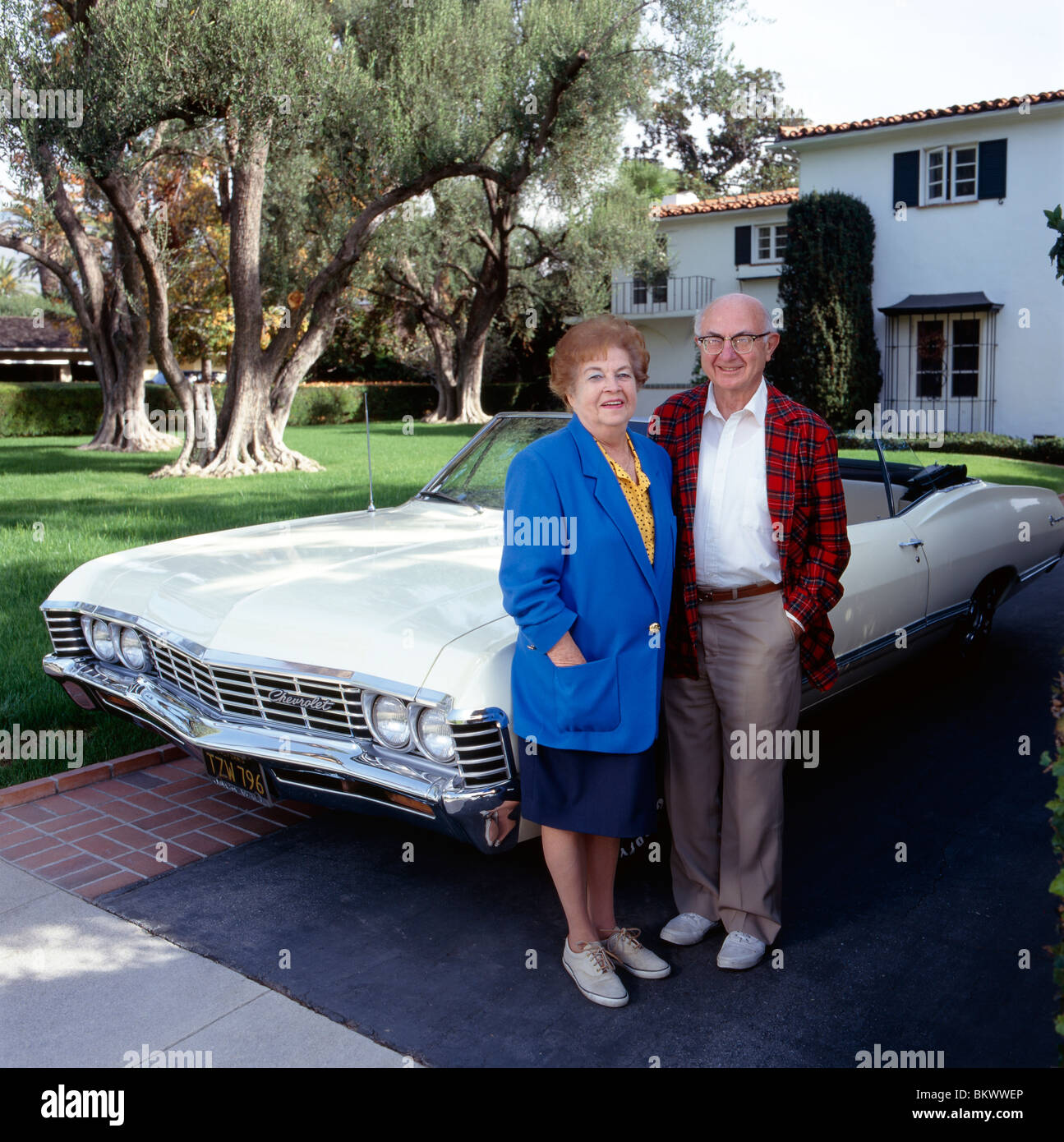 Portrait of retired couple and antique convertible Chevrolet auto outside their southern California home Stock Photo