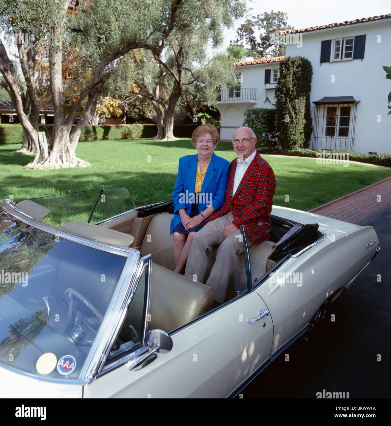 Portrait of retired couple and antique convertible Chevrolet auto outside their southern California home Stock Photo