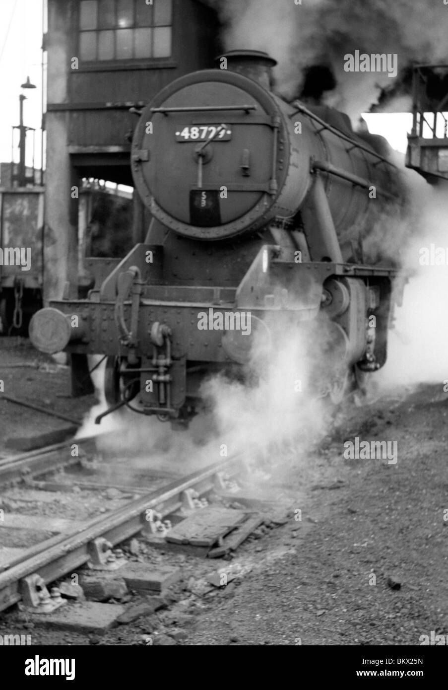engine number 48729 stanier 8f class belches smoke and steam as it leaves an engine shed during the last days of steam Stock Photo