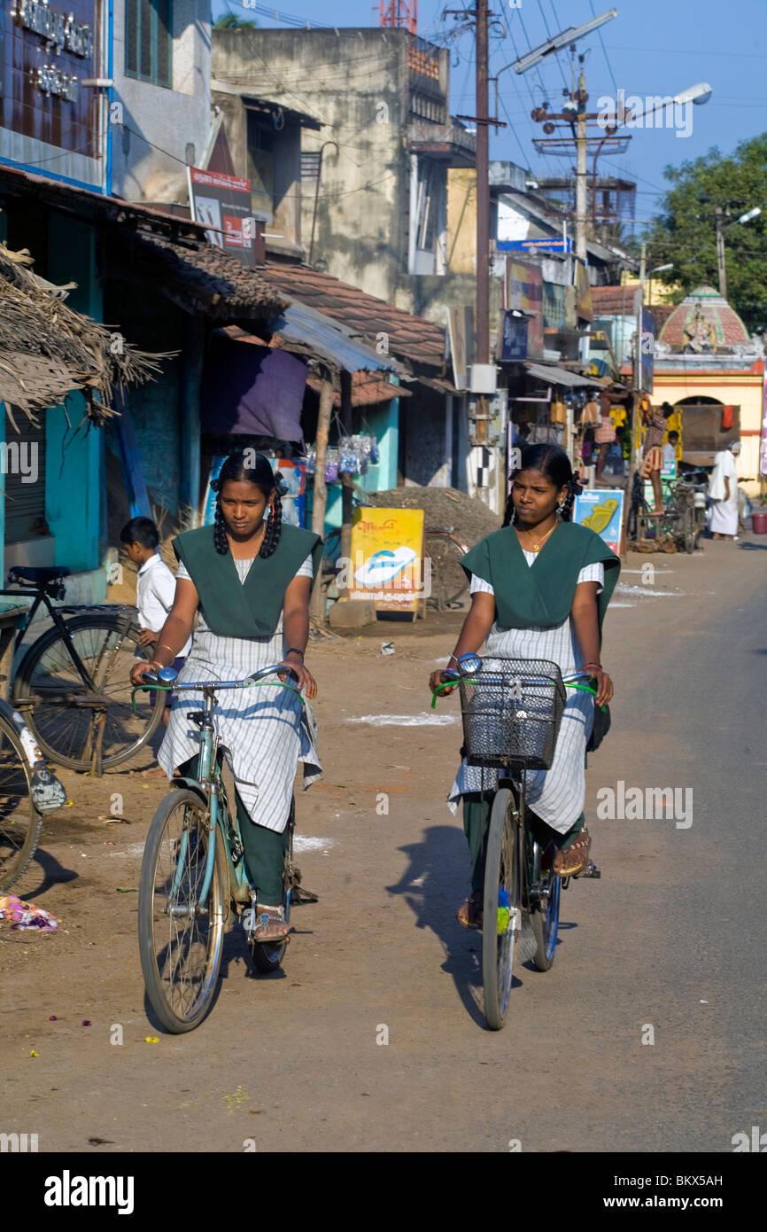 Two schoolgirls cycle along the main street, Swamimalai, Tamil Nadu, India Stock Photo