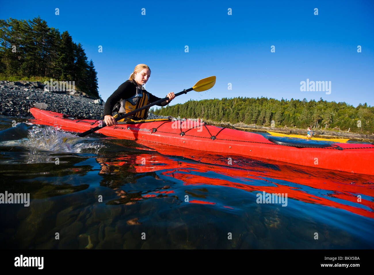 A woman sea kayaking near the Porcupine Islands in Maine's Acadia