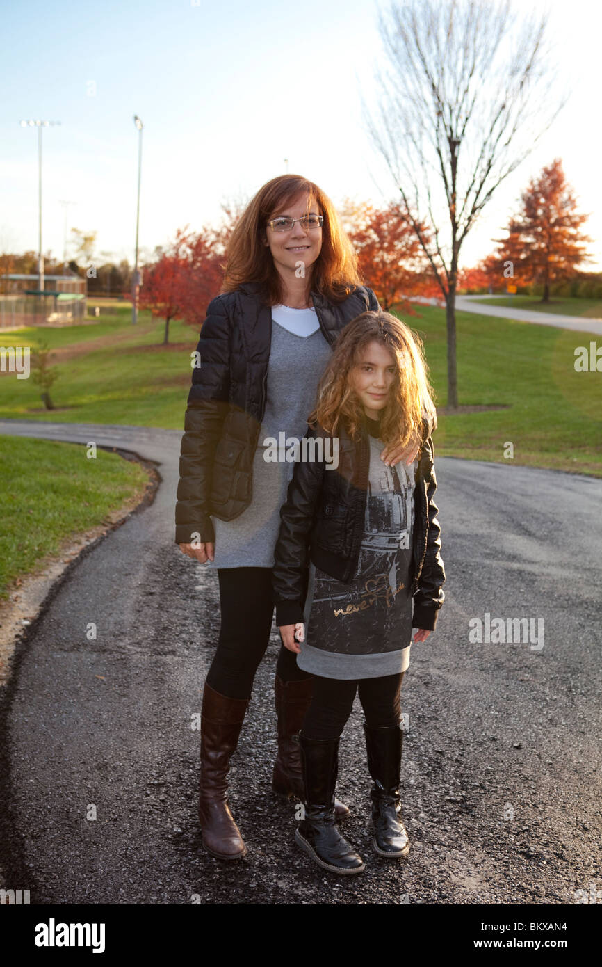Mother and daughter wearing similar clothes outdoor in a country road Stock Photo
