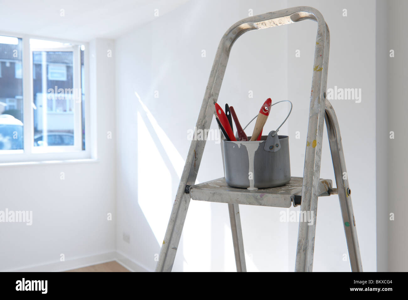 ladder with paint pot and brushes standing in empty room Stock Photo