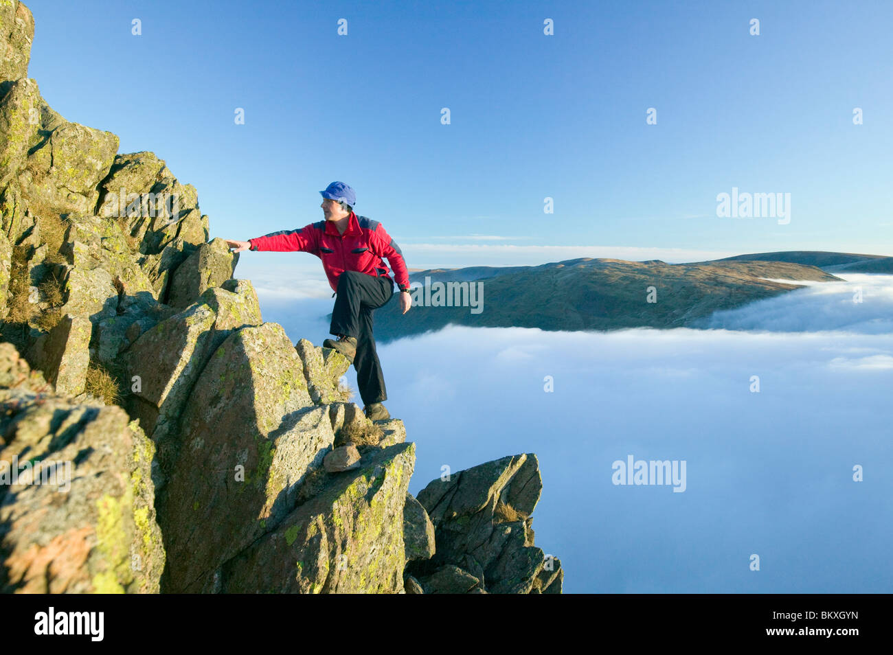 A climber on Red Screes above a temperature inversion in the Lake District UK Stock Photo