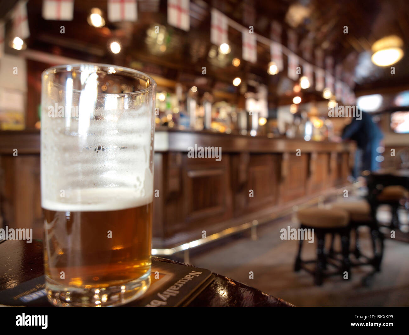 A half a pint at the Diamond pub in Ponteland, Northumberland. Glass is visible with the pub interior blurred Stock Photo