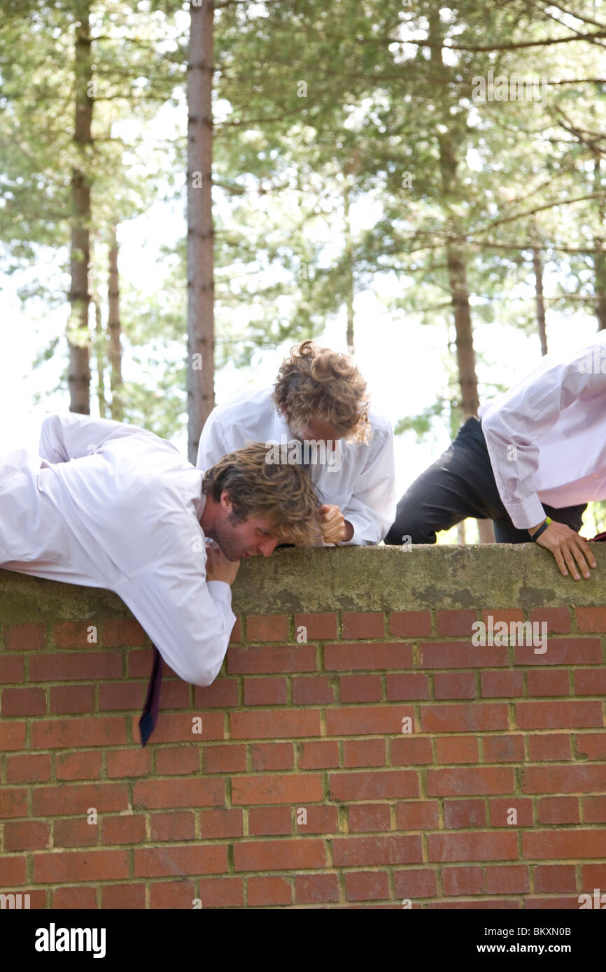 Businessmen at an obstacle course climbing a brick wall Stock Photo Alamy