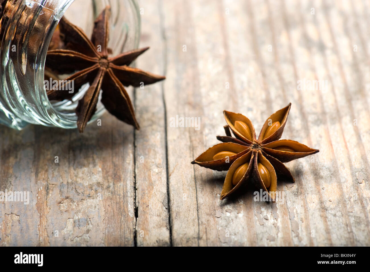 Star Anise (Illicium verum) Spilling Out Of  Jar On A Wooden Kitchen Table Stock Photo