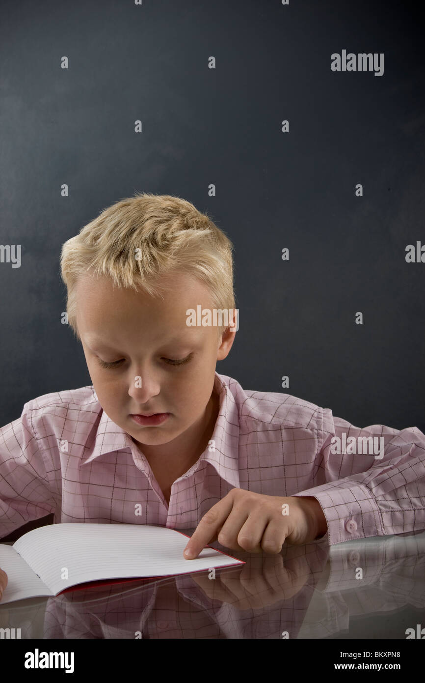 Boy sitting at desk reading Stock Photo Alamy