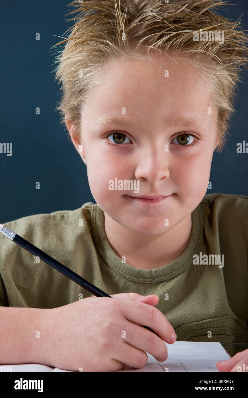 Boy sitting at desk writing Stock Photo Alamy