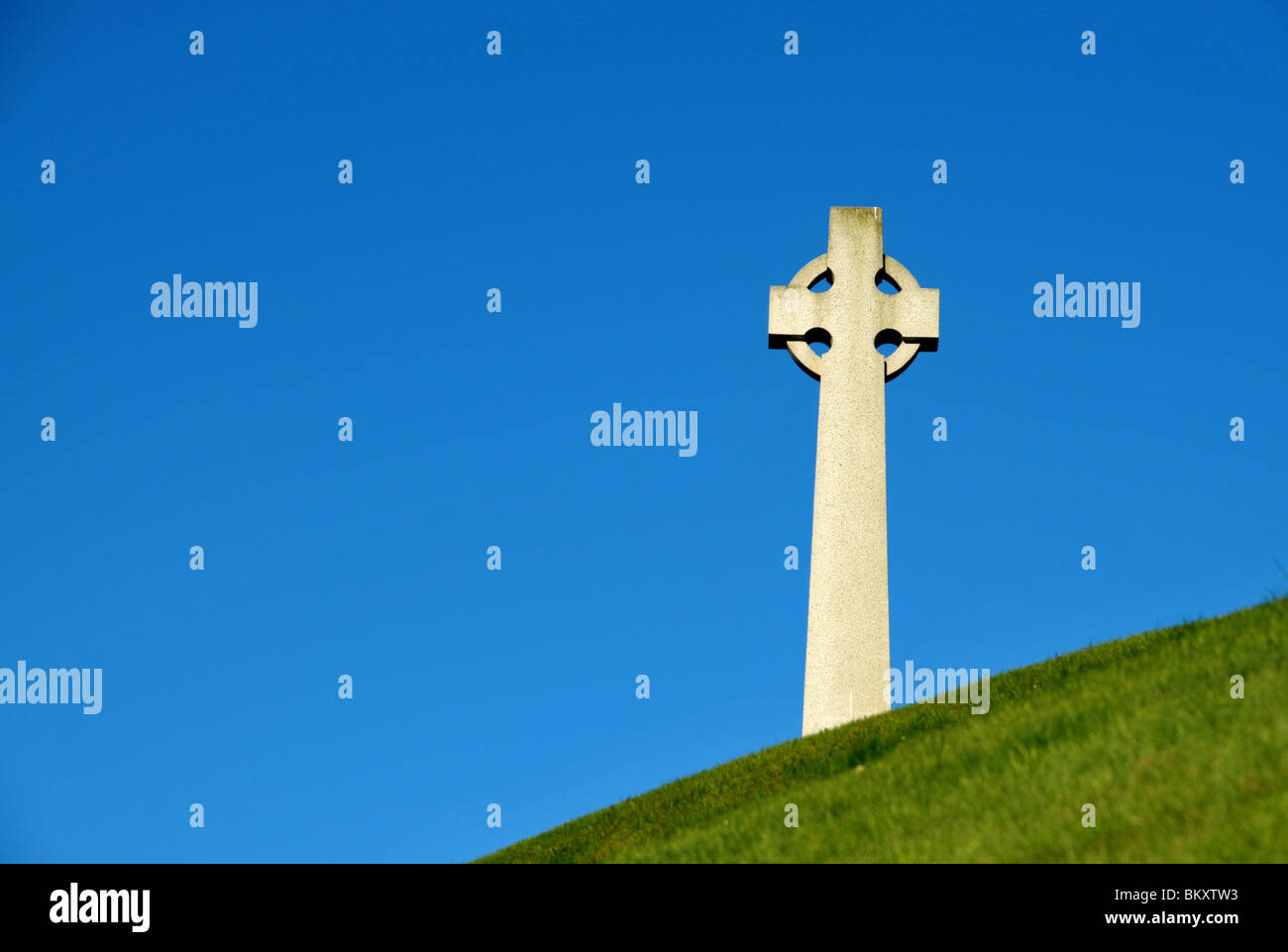 A stone Celtic  cross war memorial standing on a grassy mound  - north east of Scotland. Stock Photo