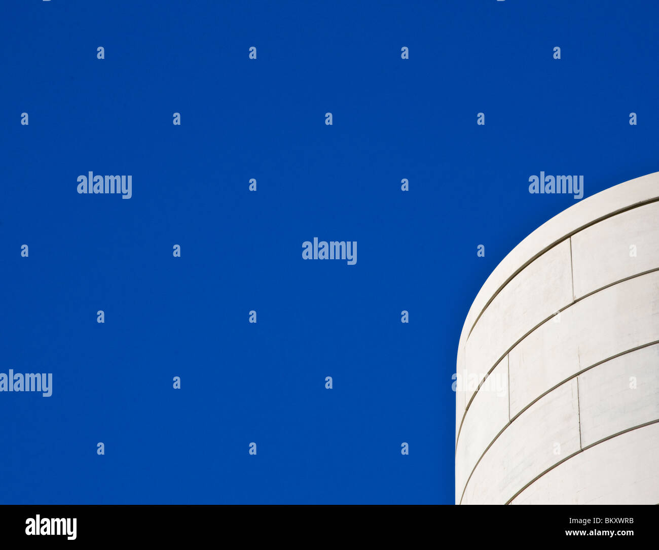 Detail of a concrete curved building against a cloudless blue sky Stock Photo