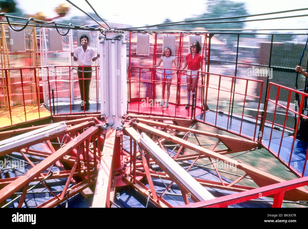 Young teen boy girls spin on tilt-up whirl ride carnival thrill scare scary fun excite centrifugal force wire mesh fast Stock Photo