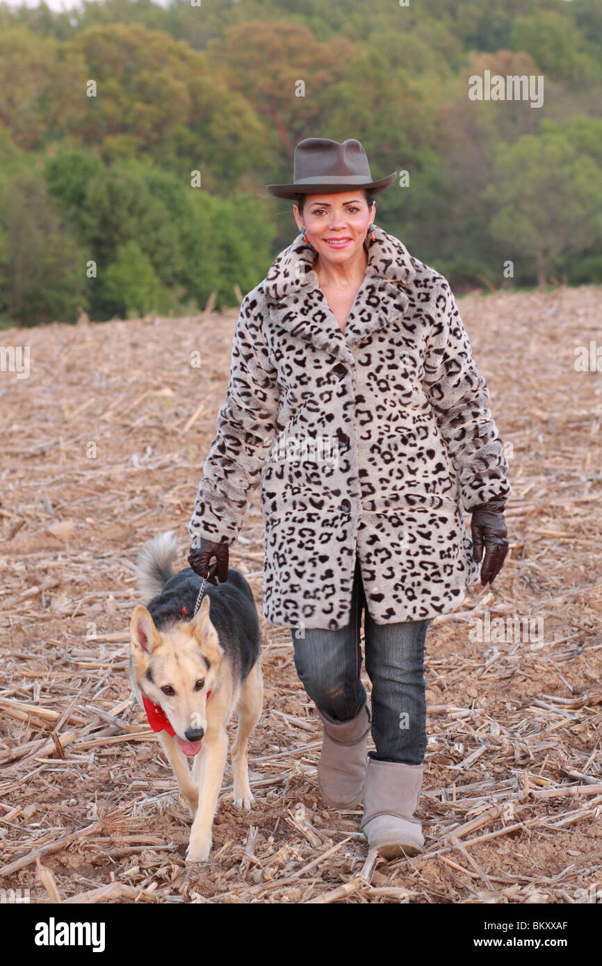 Hispanic woman walking dog in winter fall in field Stock Photo