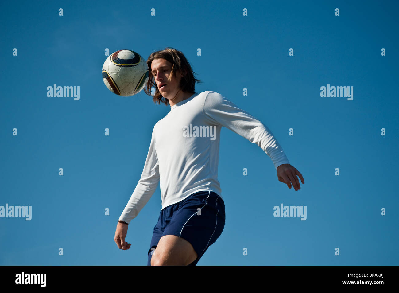 A young and athletic Caucasian male soccer player kicking around a ball outside Stock Photo