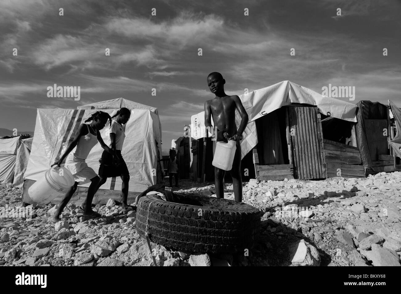 A child stands next to tents made of sheets at a temporary makeshift encampment in Port-au-Prince after a 7.0 magnitude earthquake struck Haiti on 12 January 2010 Stock Photo