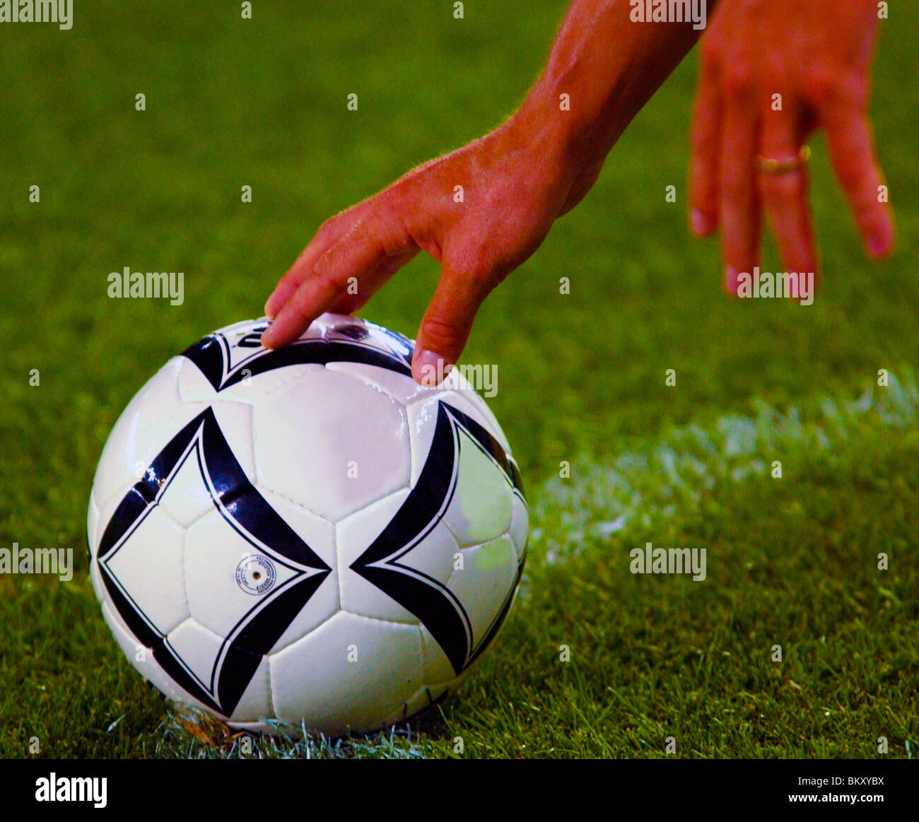 Football player places hand on football to position for free kick Stock Photo
