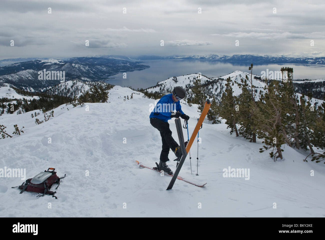 A young man takes his skins off his skis after skinning up a mountain high above Lake Tahoe, Nevada. Stock Photo