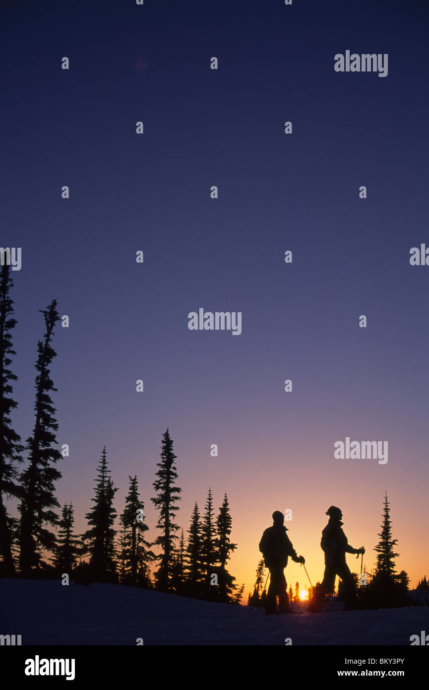 Couple snowshoeing during a colorful sunset in Mt. Rainier National Park, Washington. Stock Photo