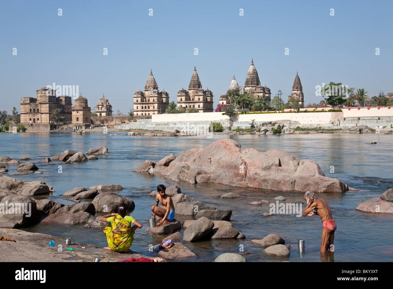 People bathing in the Petwa river.On the background the Royal cenotaphs. Orchha. Madhya Pradesh. India Stock Photo