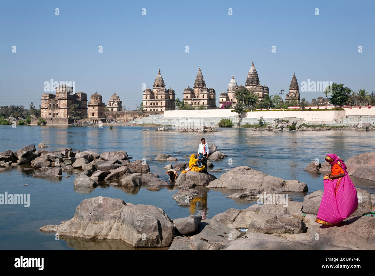 People bathing in the Petwa river.On the background the Royal cenotaphs. Orchha. Madhya Pradesh. India Stock Photo