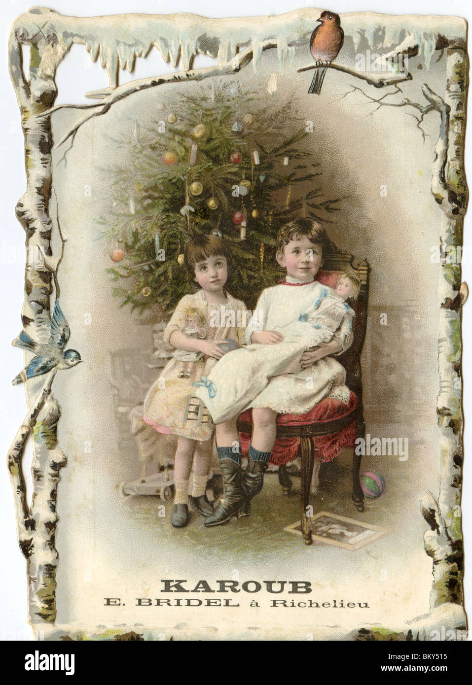 Two Siblings and their Dolls Posing in front of the Christmas Tree Stock Photo