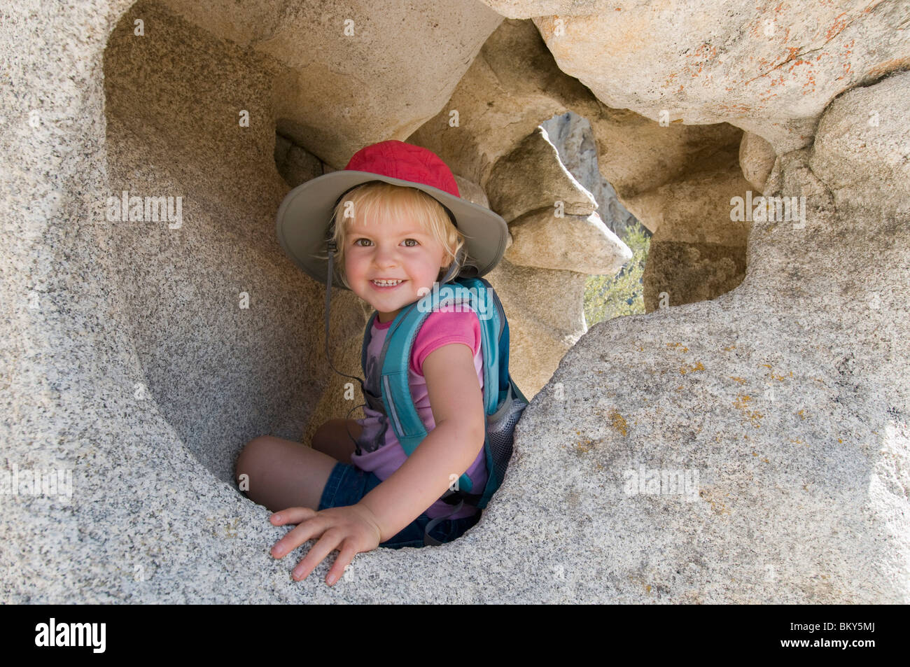A young smiling girl in a granite cave in the City of Rocks National Reserve, Almo, Idaho. Stock Photo