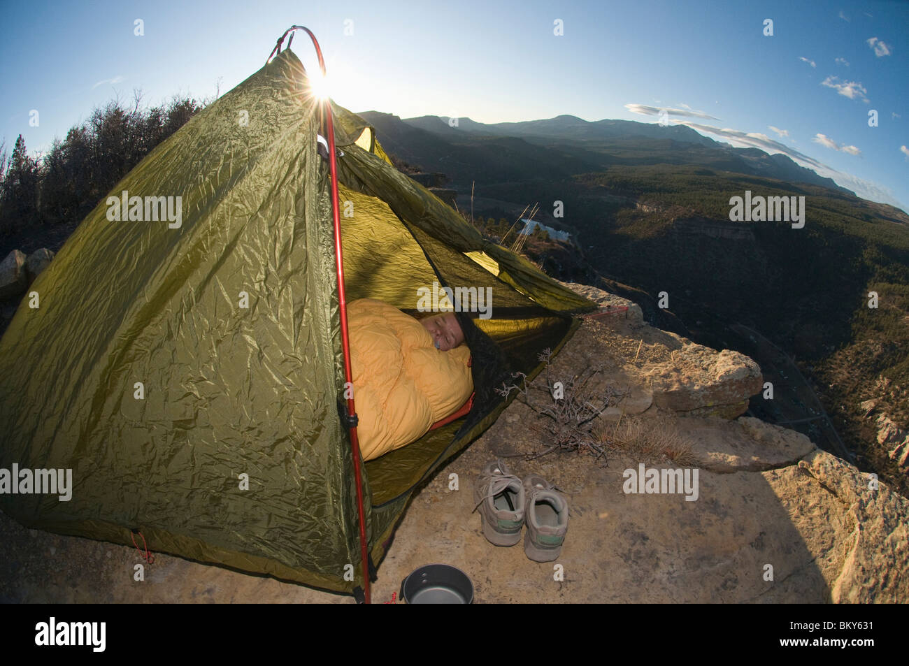 A woman in tent in sleeping bag at sunset on Animas Mountain, Durango, Colorado. Stock Photo