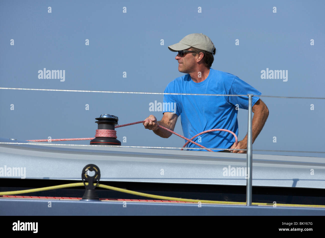 A crew member trims sheet onboard sailing yacht. Stock Photo