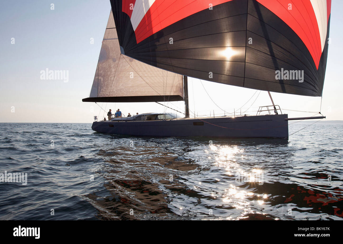 A crew races a modern ocean-going sailing yacht under spinnaker. Stock Photo